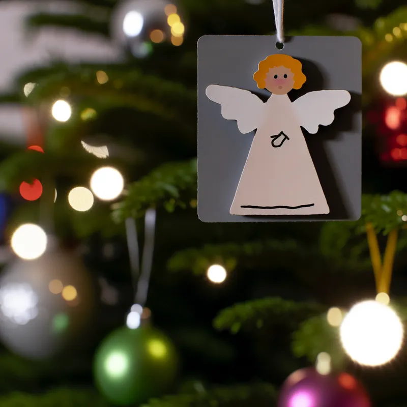 Klein, schattig papieren engel ornament dat aan een kerstboom hangt
